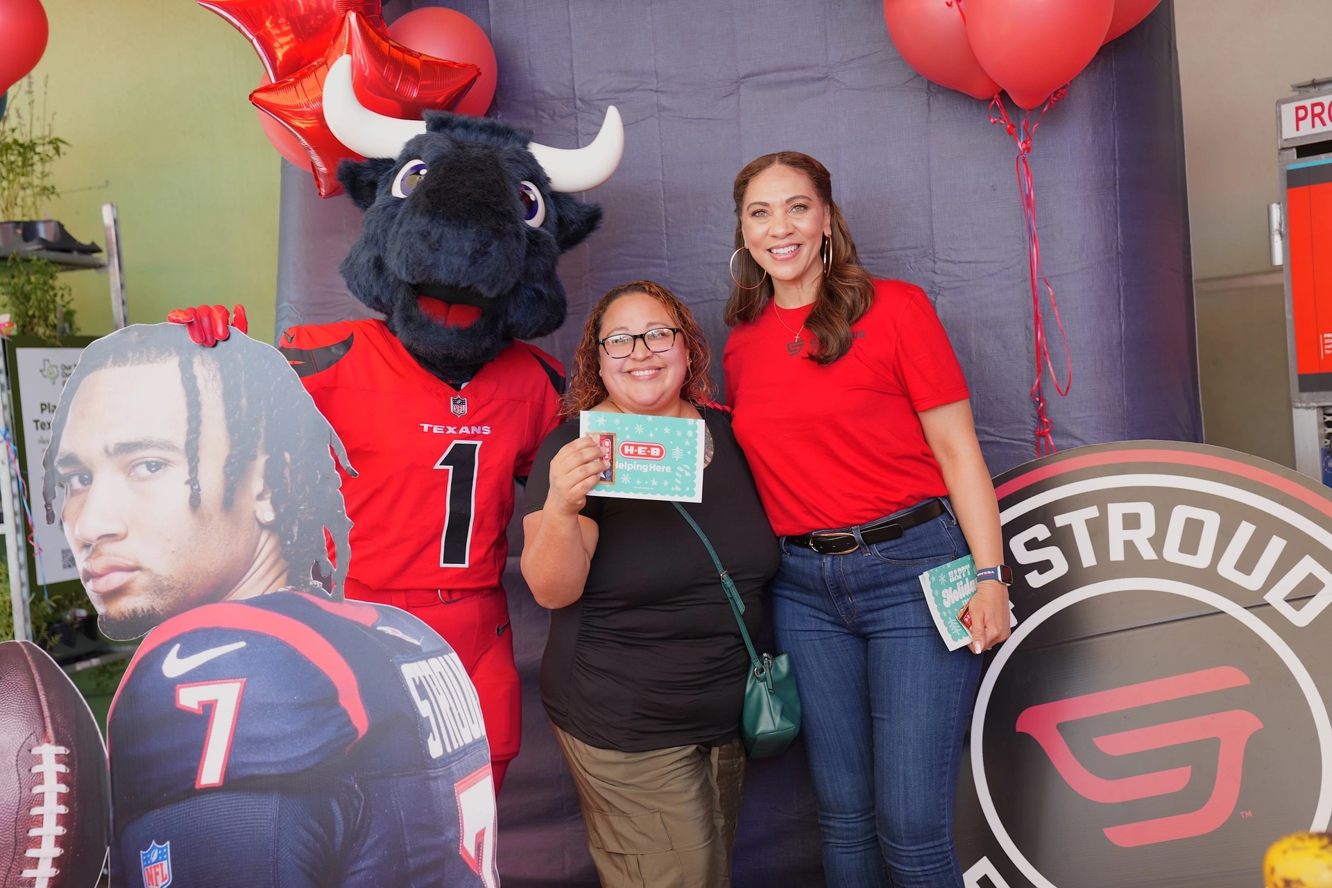 Two women posing with mascot and cutout.