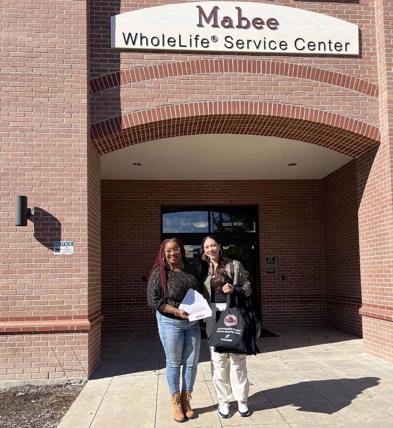 Two people smiling outside service center entrance.