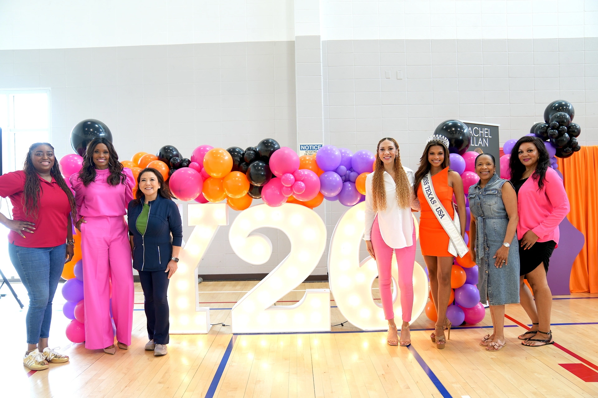 Group posing in front of colorful balloons.