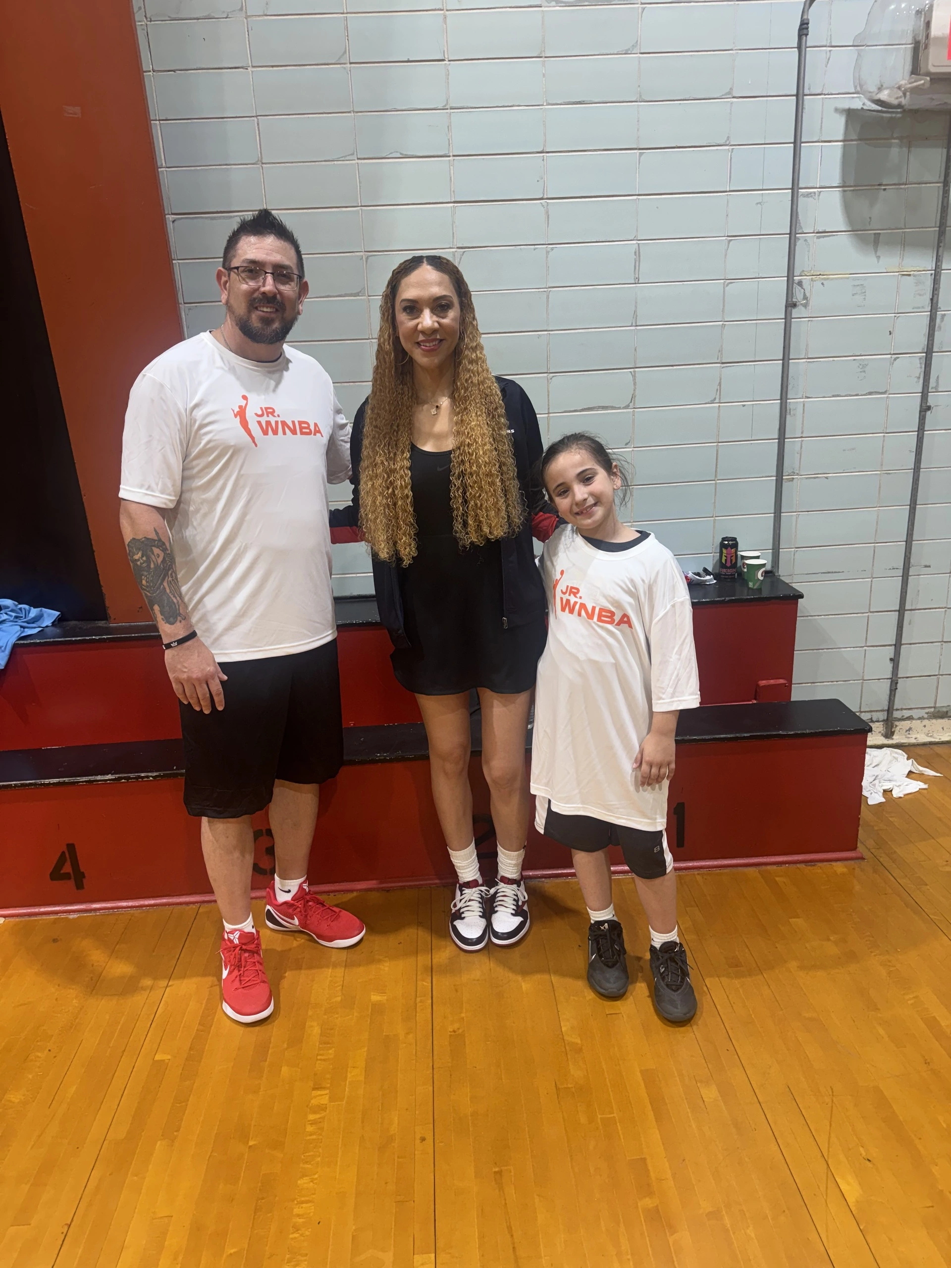 Three people posing on a basketball court.