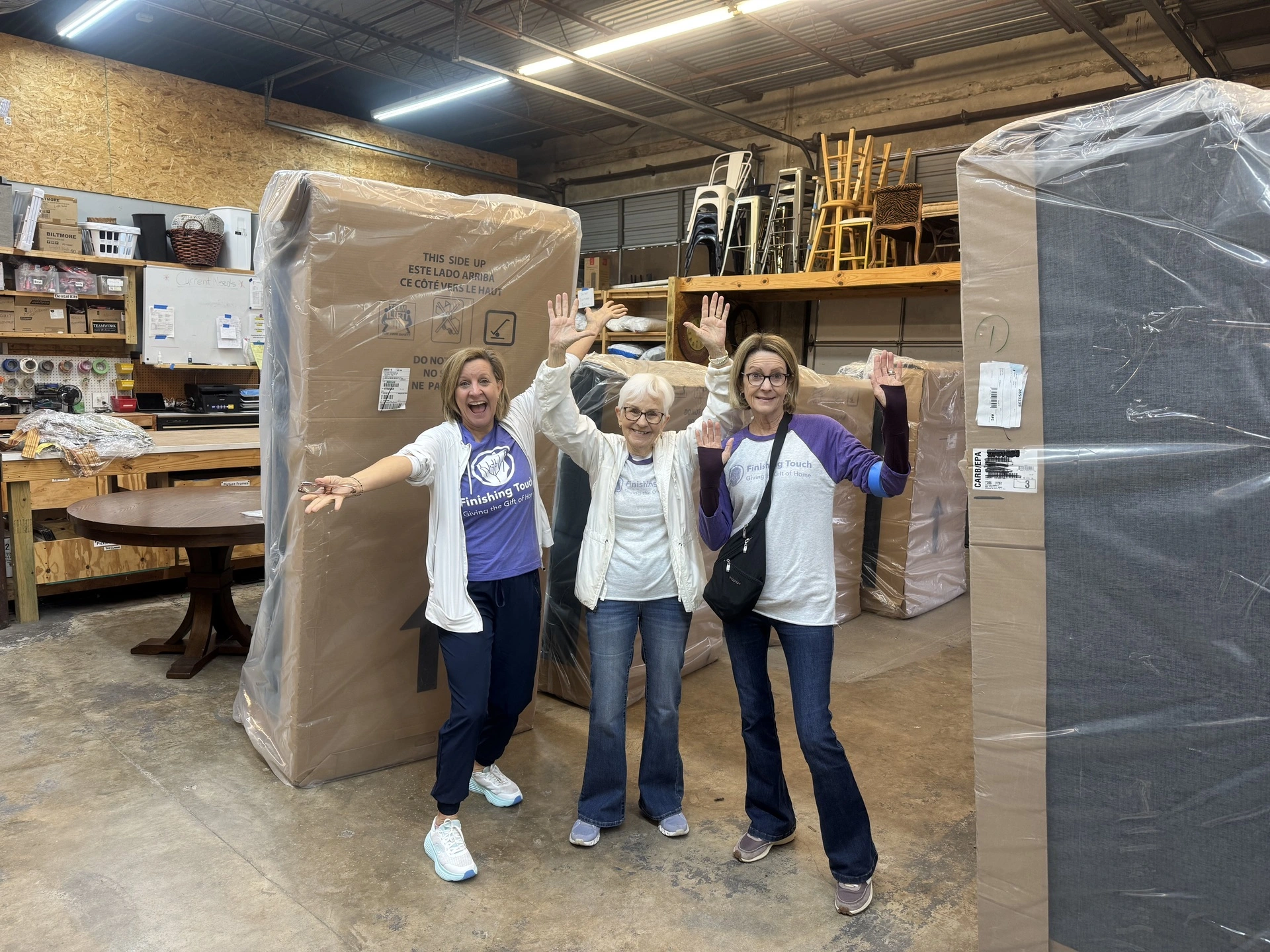Three women posing in a warehouse.