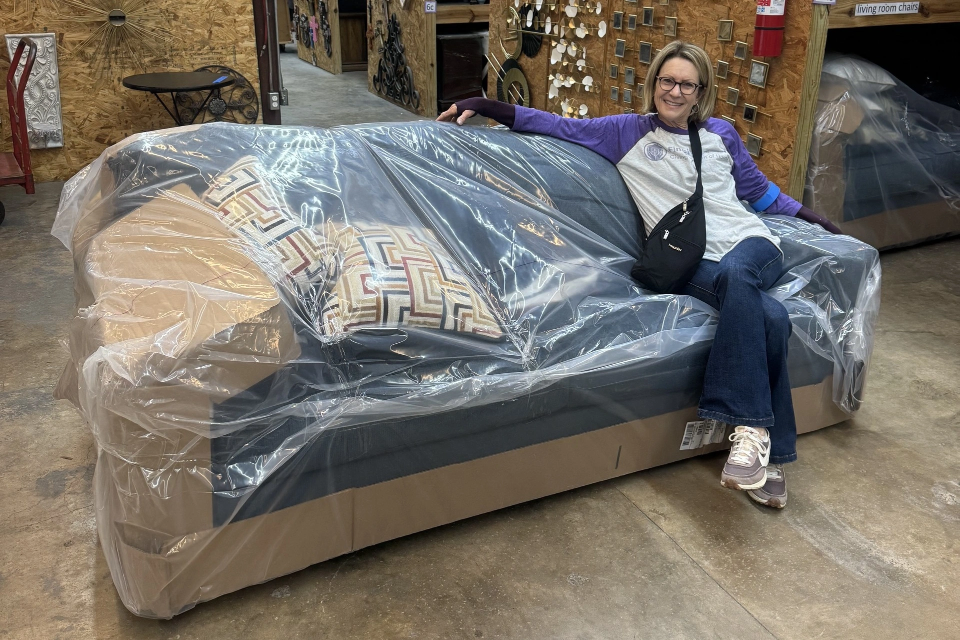 Person sitting on wrapped sofa in store.